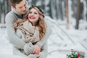 Bride and groom are hugging in the winter forest. Couple in love. Winter wedding ceremony.