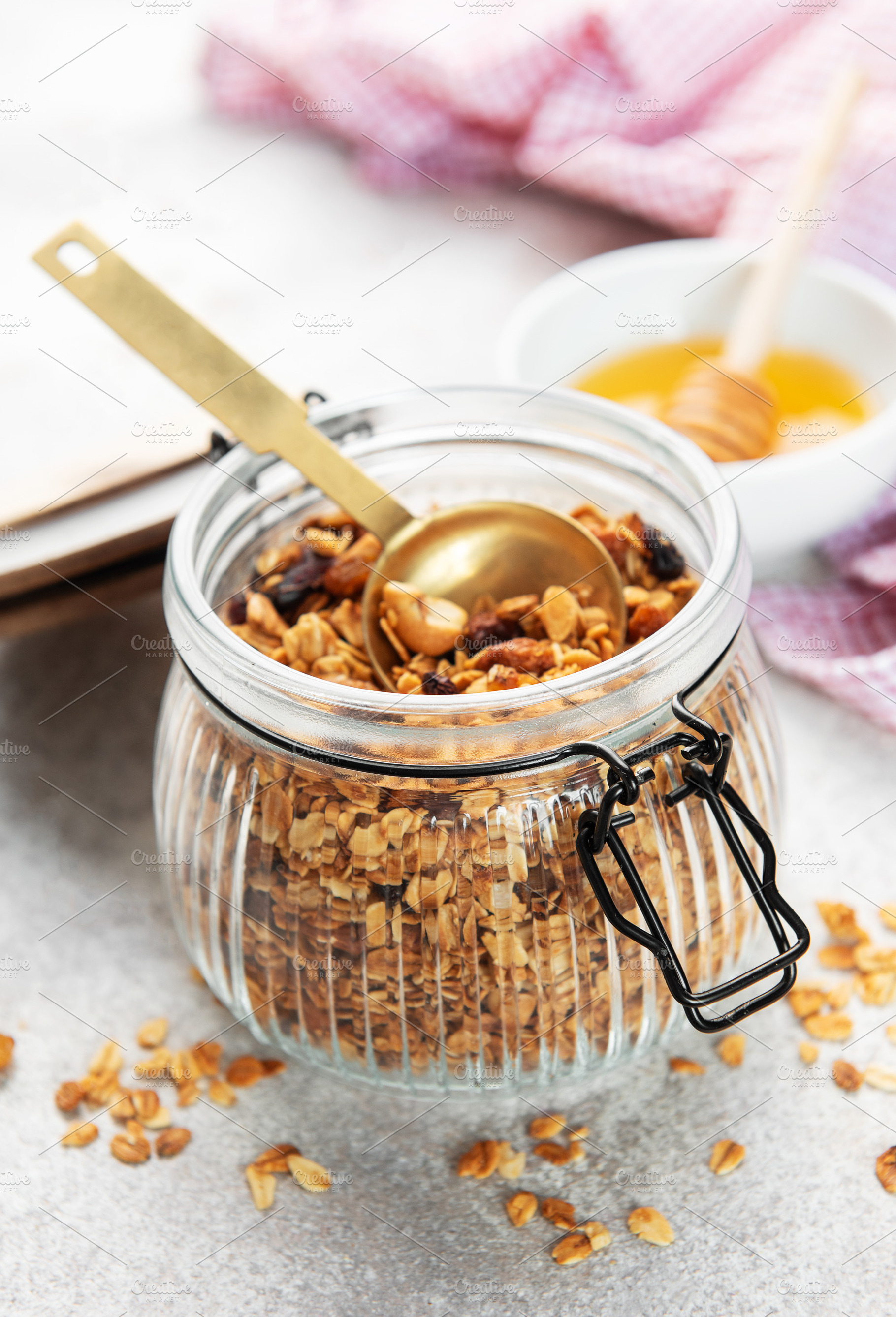 Granola cereal with nuts in a glass jar and spoon, healthy break, a Food & Drink Photo by Olena Rudo