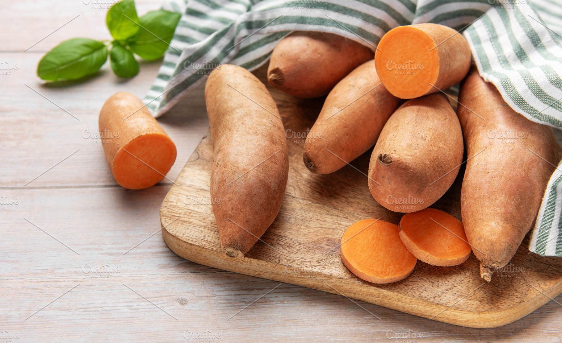 Sweet potatoes on wooden board with basil leaves, a Food & Drink Photo by Olena Rudo