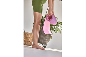 Woman unrolling pink yoga mat on, a Person Photo by wip3out