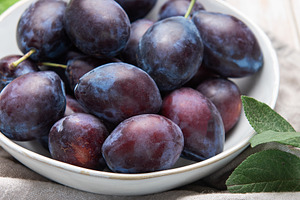Fresh ripe plums in white bowl on table, a Food & Drink Photo by Olena Rudo