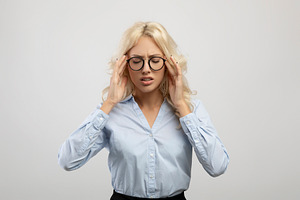 Young tired female entrepreneur suffering from headache and touching temples, s, a Photo by Prostock-Studio