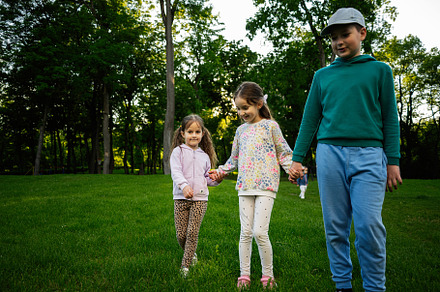 Children holding hands outdoors in a green field on a sunny day, a Person Photo by AS photostudio