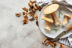 Fresh mushrooms on plate with dried mushrooms and knife, a Food & Drink Photo by Olena Rudo