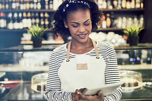 Smiling African entrepreneur working in her cafe with a tablet