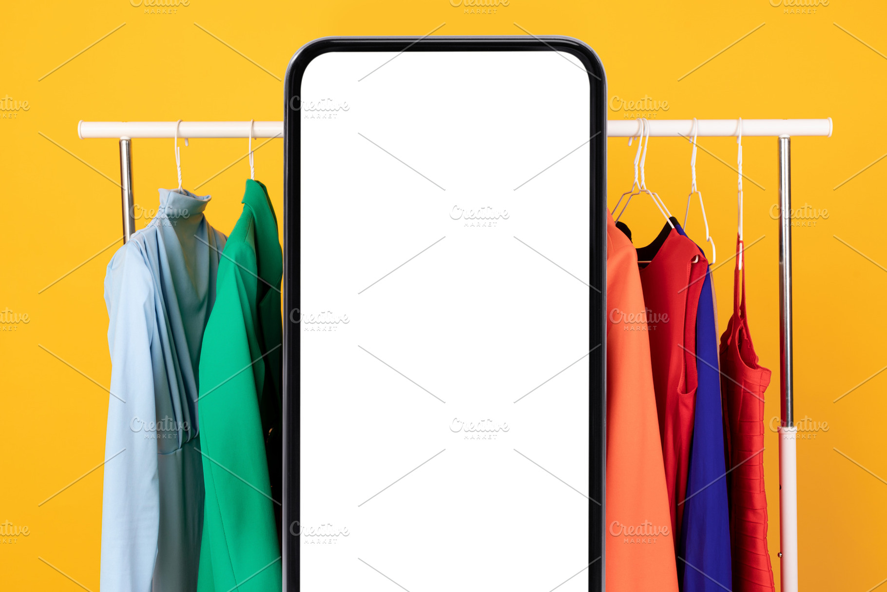 Big Smartphone Blank Screen Standing Near Clothing Rail, Yellow Background, a Photo by Prostock-Studio