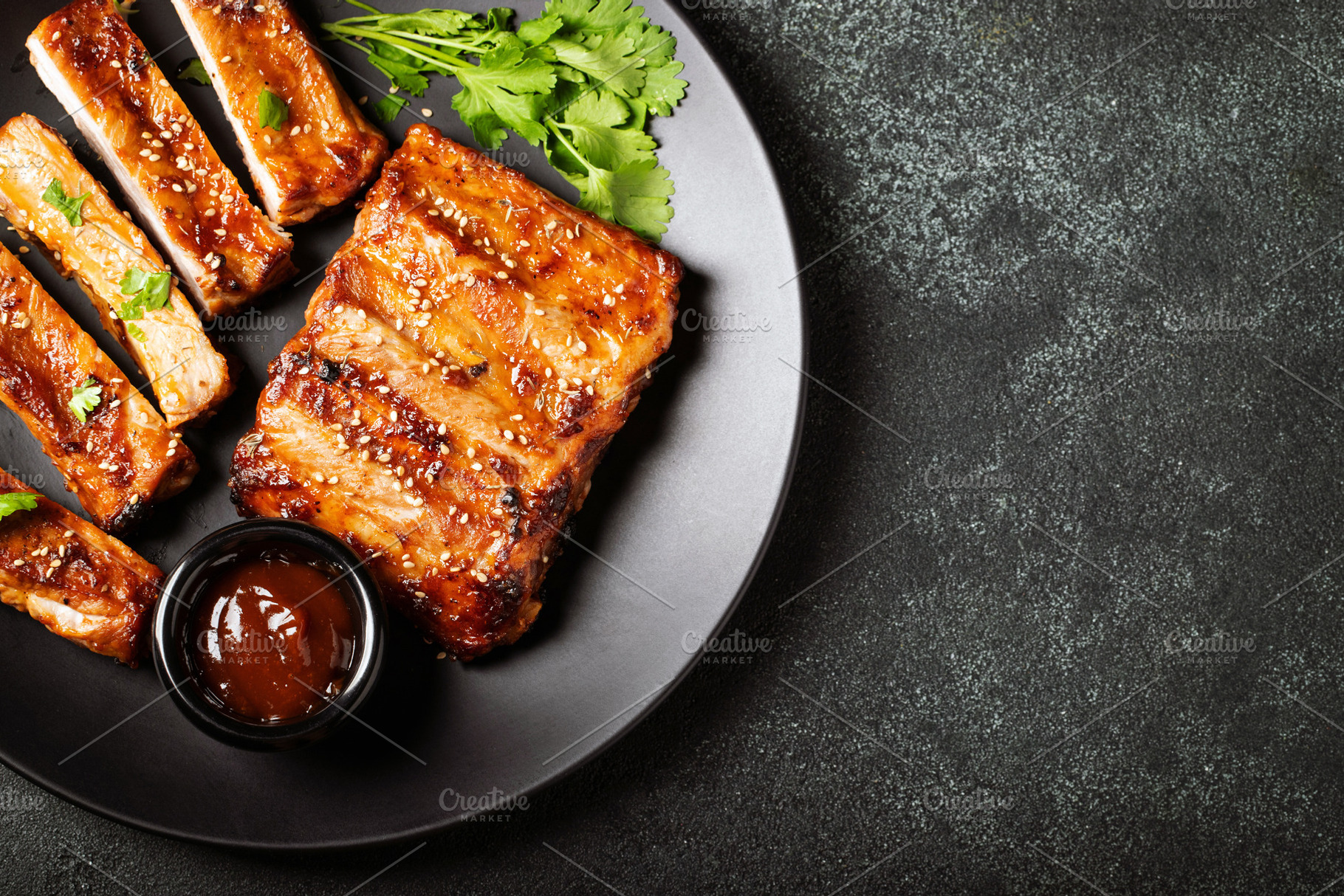 Hot grilled spare ribs from a summer BBQ served on a plate with sauce. Top view, a Food & Drink Photo by Budarinphoto