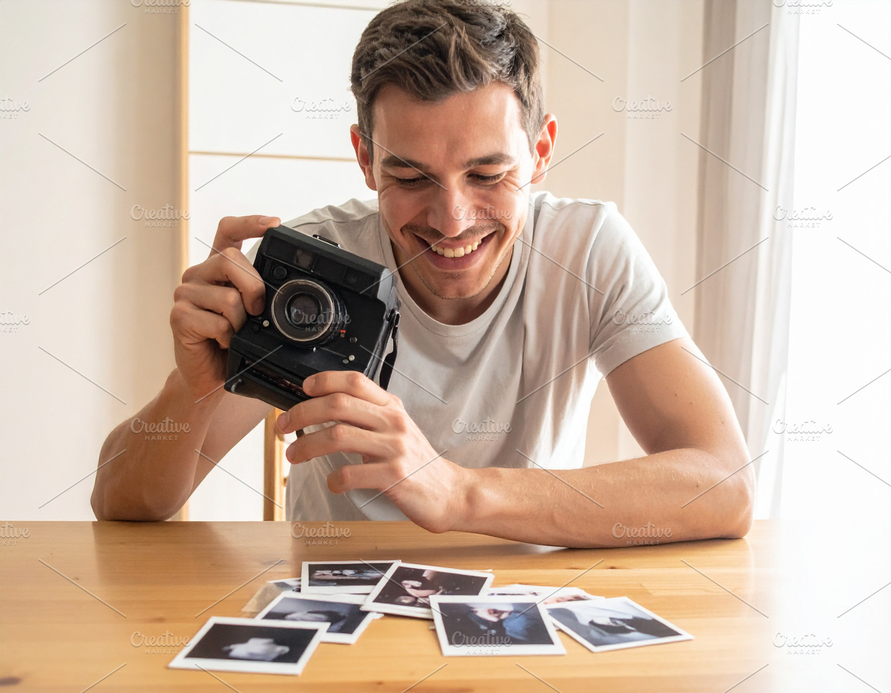 Man holding analog camara while smiling at looking print photo o, a Person Photo by DanFLCreativo