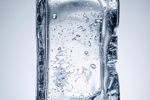 Ice block on a surface melting, forming a puddle of clear water,, a Photo by Studio ANNA