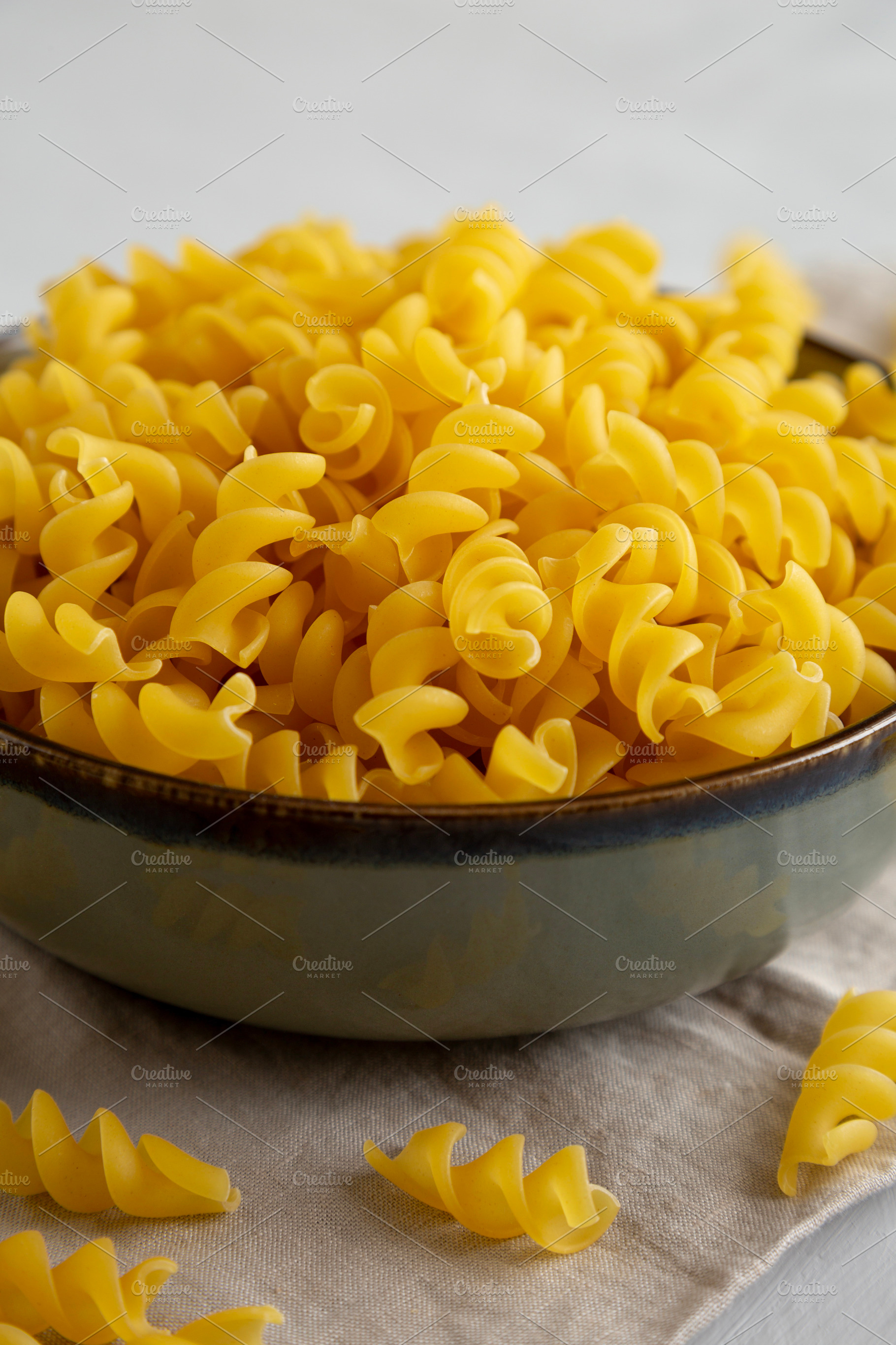 Raw Dry Organic Fusillini Pasta in a Bowl, side view., a Food & Drink Photo by LiudmylaChuhunova