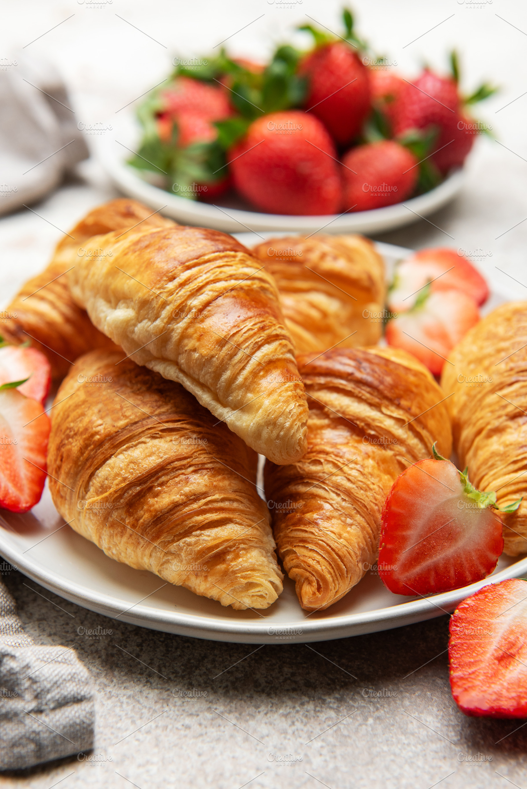 Freshly baked croissants served with juicy strawberries on white, a Food & Drink Photo by Olena Rudo