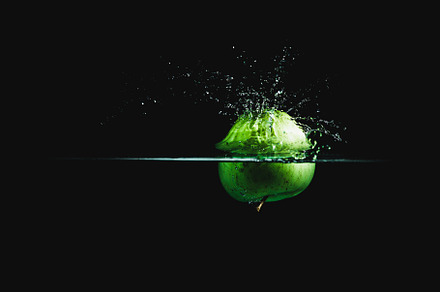 Green apple dropping in water 