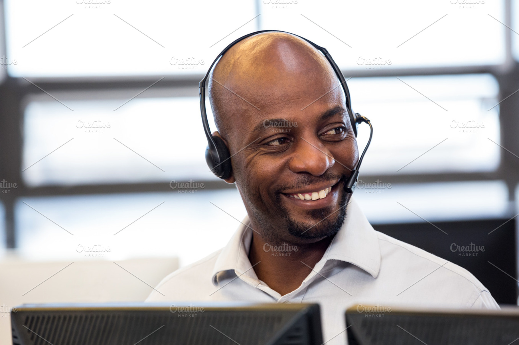 Man working on computer with headset, a Photo by wavebreak