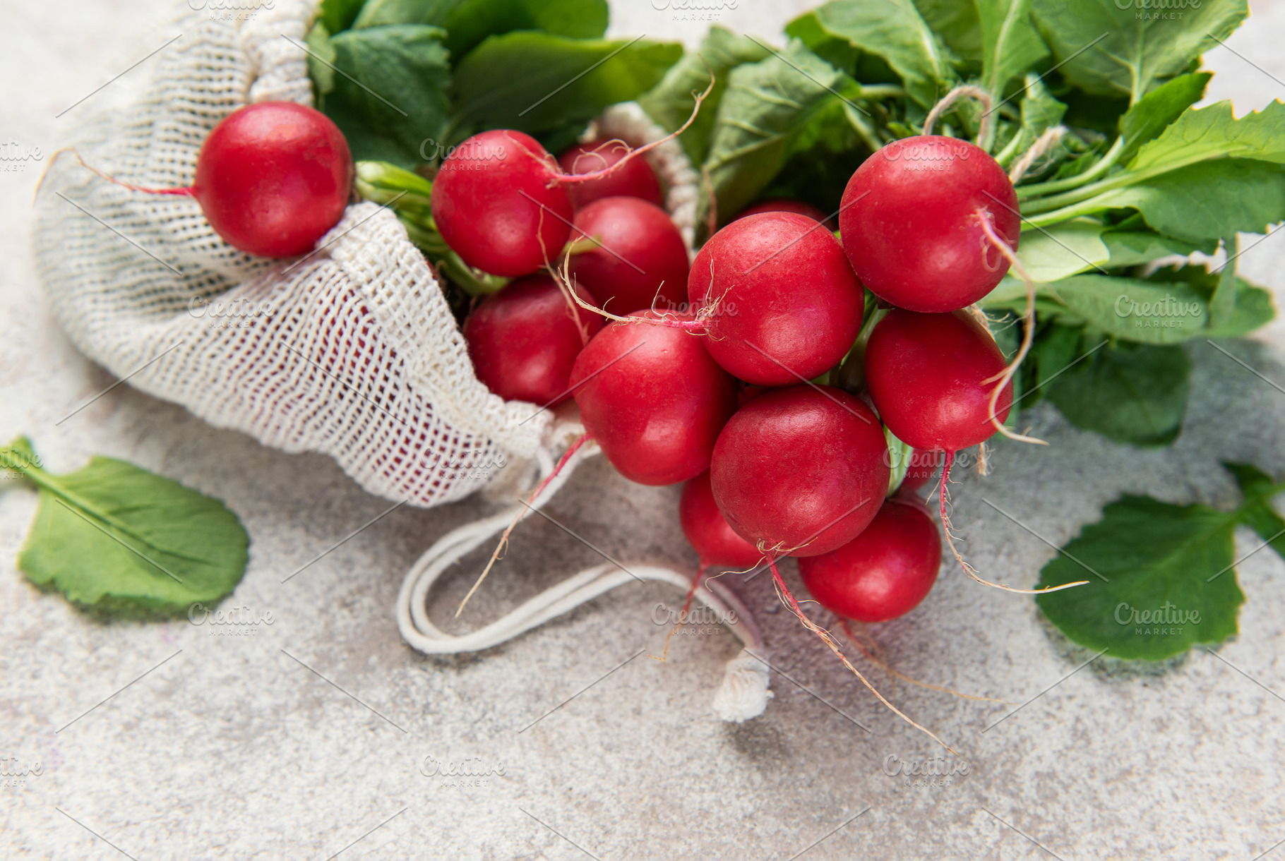 Fresh organic radishes spilling from a reusable mesh bag, a Food & Drink Photo by Olena Rudo
