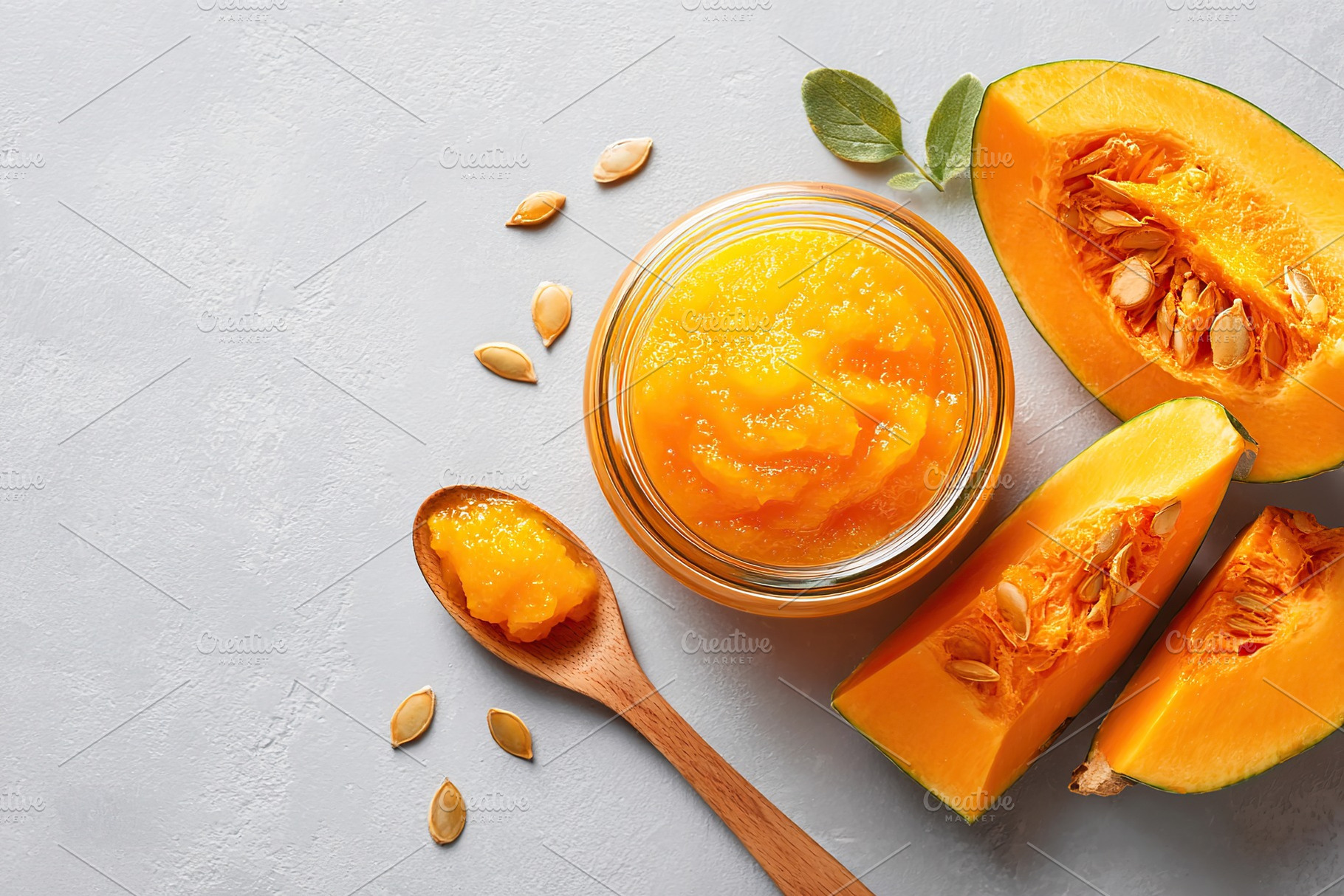 Fresh pumpkin puree in a jar with sliced pumpkin and seeds on a gray background, a Food & Drink Photo by AlyaAnd
