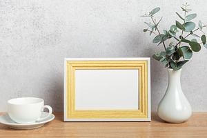 Empty photo frame, coffee cup and eucalyptus branches on table, a Background Photo by Olena Rudo