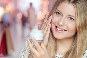 Happy woman applying a moisturizing cream to her face, promoting, a Person Photo by Studio ANNA