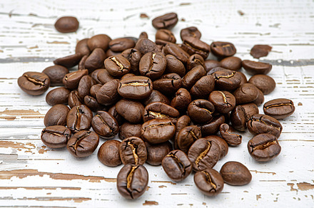 Heap of coffee beans on wooden table, a Food & Drink Photo by AlyaAnd