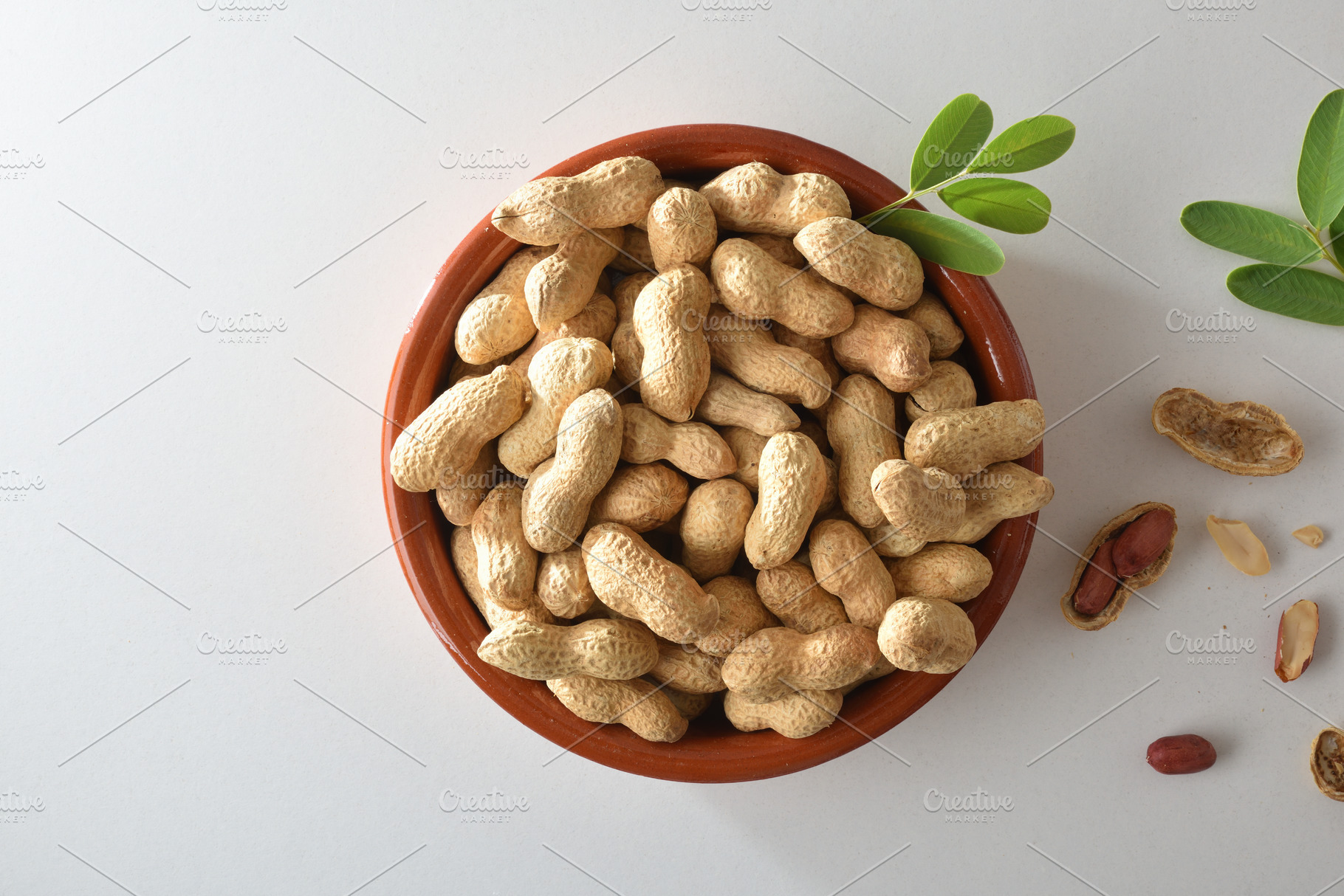 Heap of peanuts in clay bowl with leaves in the center, a Food & Drink Photo by Davizro's Market
