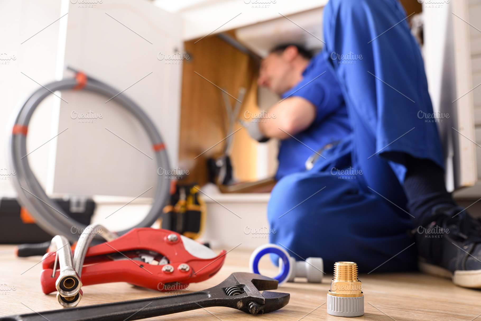 Plumbing material and a plumber repairing a kitchen sink, a Business Photo by Davizro's Market
