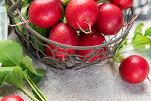 Fresh red radishes in a basket on a concrete surface, a Food & Drink Photo by Olena Rudo