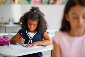 Focused schoolgirl writing notes in, a Person Photo by HalfPoint