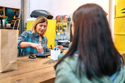Female cashier passing credit card through store terminal to charge purchased i, a Person Photo by davidpereiras