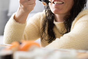 Woman eating sushi with chopsticks at home, a Person Photo by etorres69