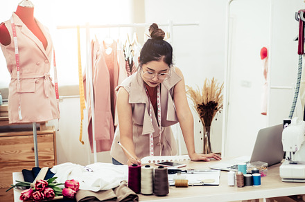 Attractive Asian female fashion designer working in home office, a Beauty & Fashion Photo by Ministocker