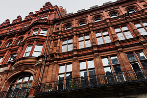 Victorian red brick building facade with ornate windows and iron balcony in Liv