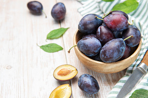 Fresh plums in wooden bowl with knife, a Food & Drink Photo by Olena Rudo