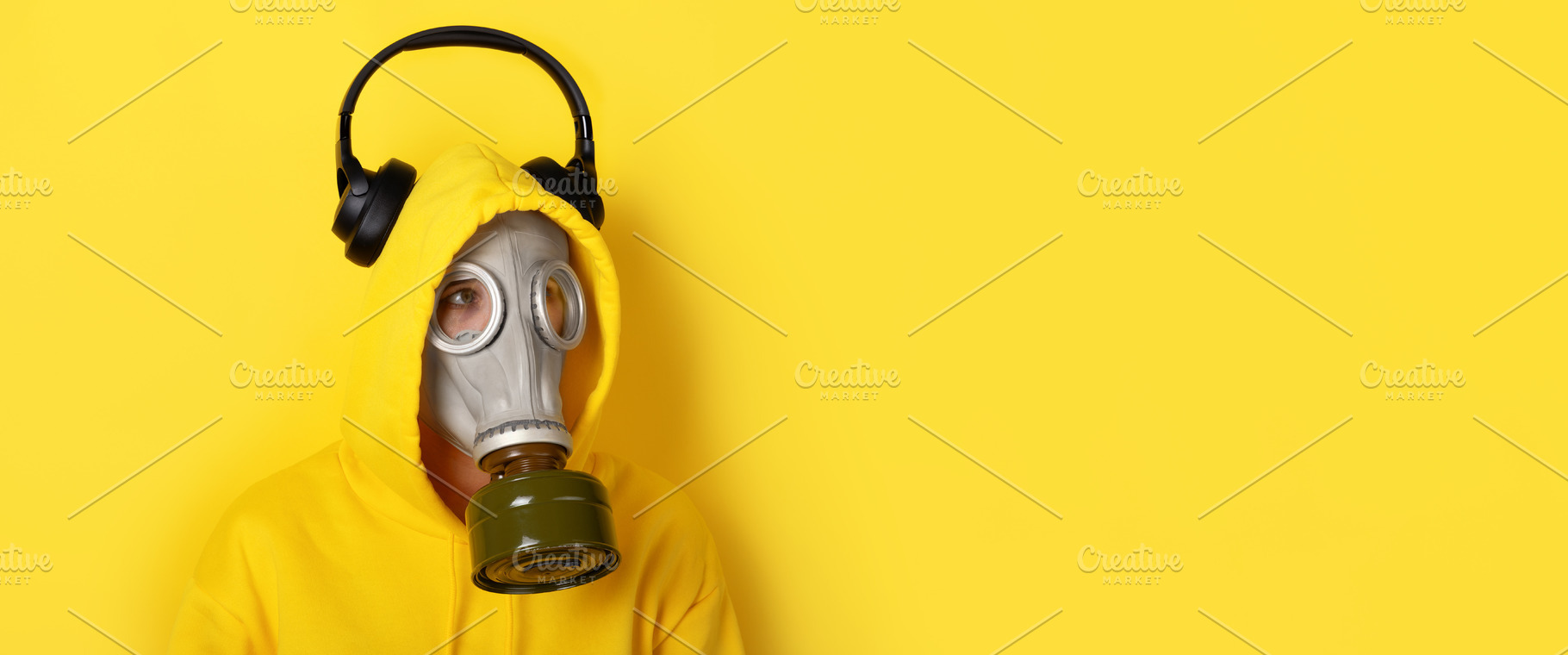 Person wearing a yellow hoodie, gas mask, and black headphones o, a Person Photo by Ales Munt