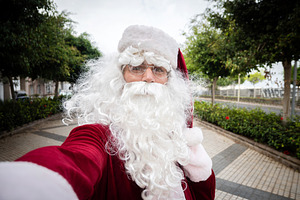 Santa Claus taking selfie outdoors on city promenade, a Photo by etorres69