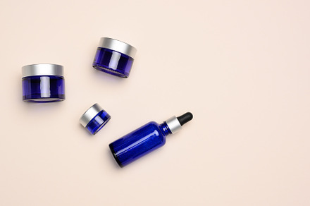 glass cosmetic blue bottles with a pipette  and jar on a beige b, a Beauty & Fashion Photo by ndanko