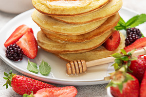 Stack of pancakes with berries, honey, and mint, a Food & Drink Photo by Olena Rudo