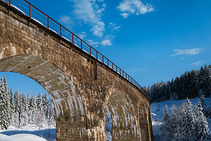 Stone viaduct (arch bridge) on railway through mountain snowy fi, a Nature Photo by YuriyB
