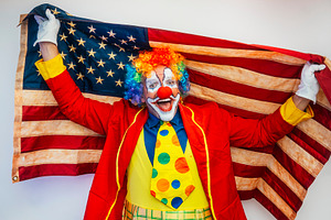 Excited clown holding American national flag, a Person Photo by karrastock