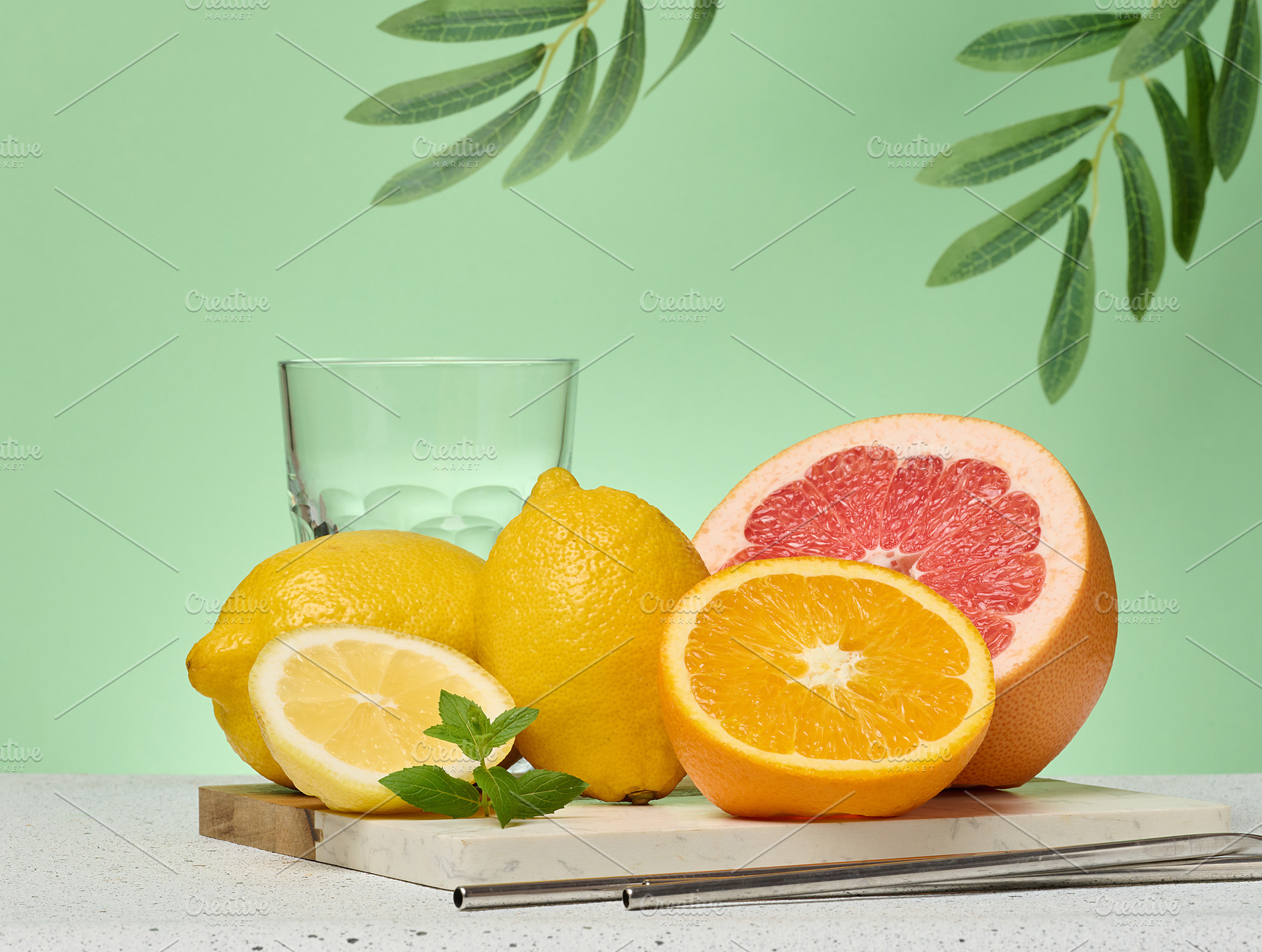 Grapefruit, orange and empty glass on green background, a Food & Drink Photo by ndanko