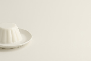 White ceramic jelly mold on plate against neutral background, co, a Photo by Dvoevnore photos