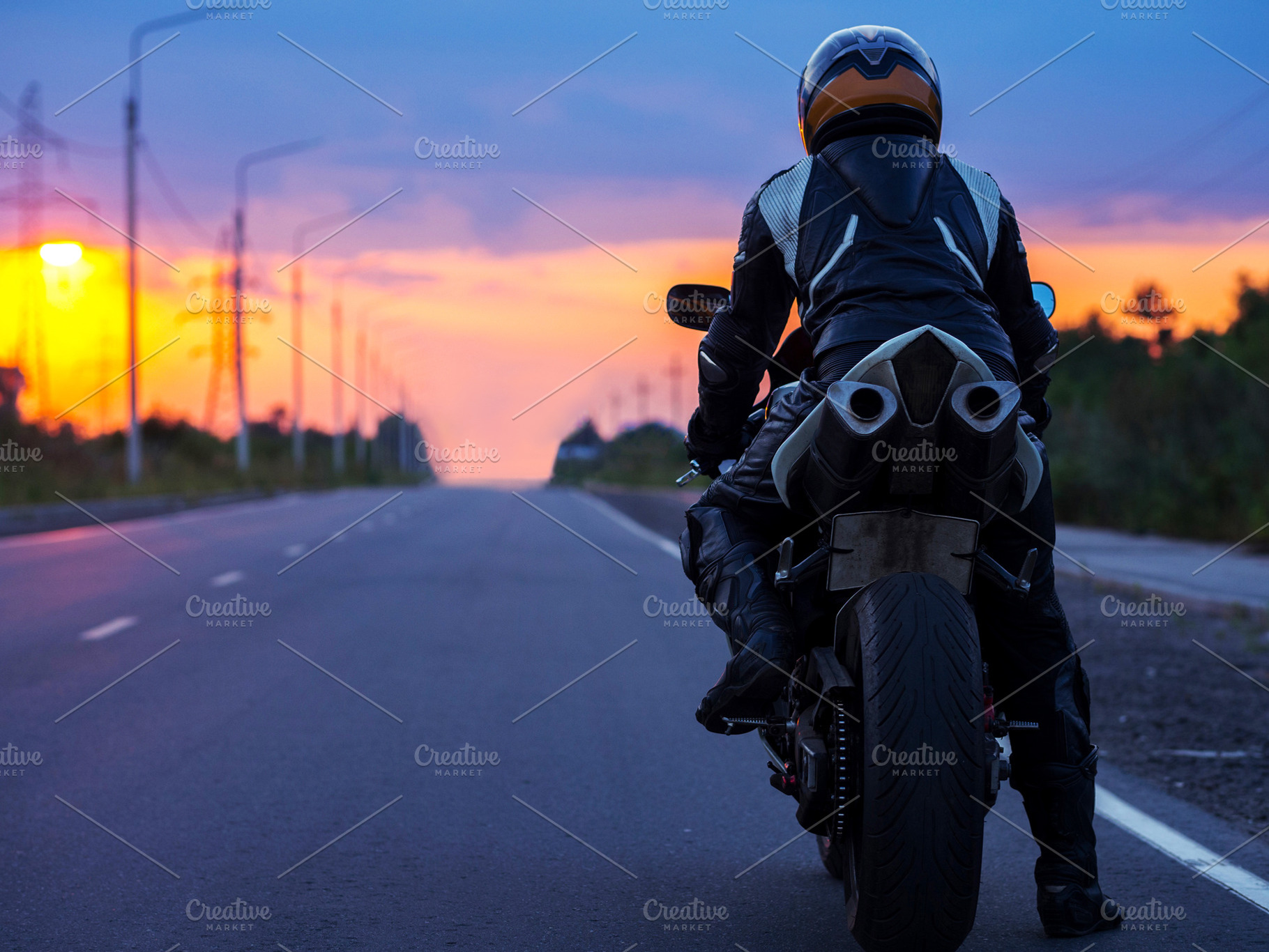 motorcyclist stands on an empty road at sunset , back view , cop, a Person Photo by PavelKant