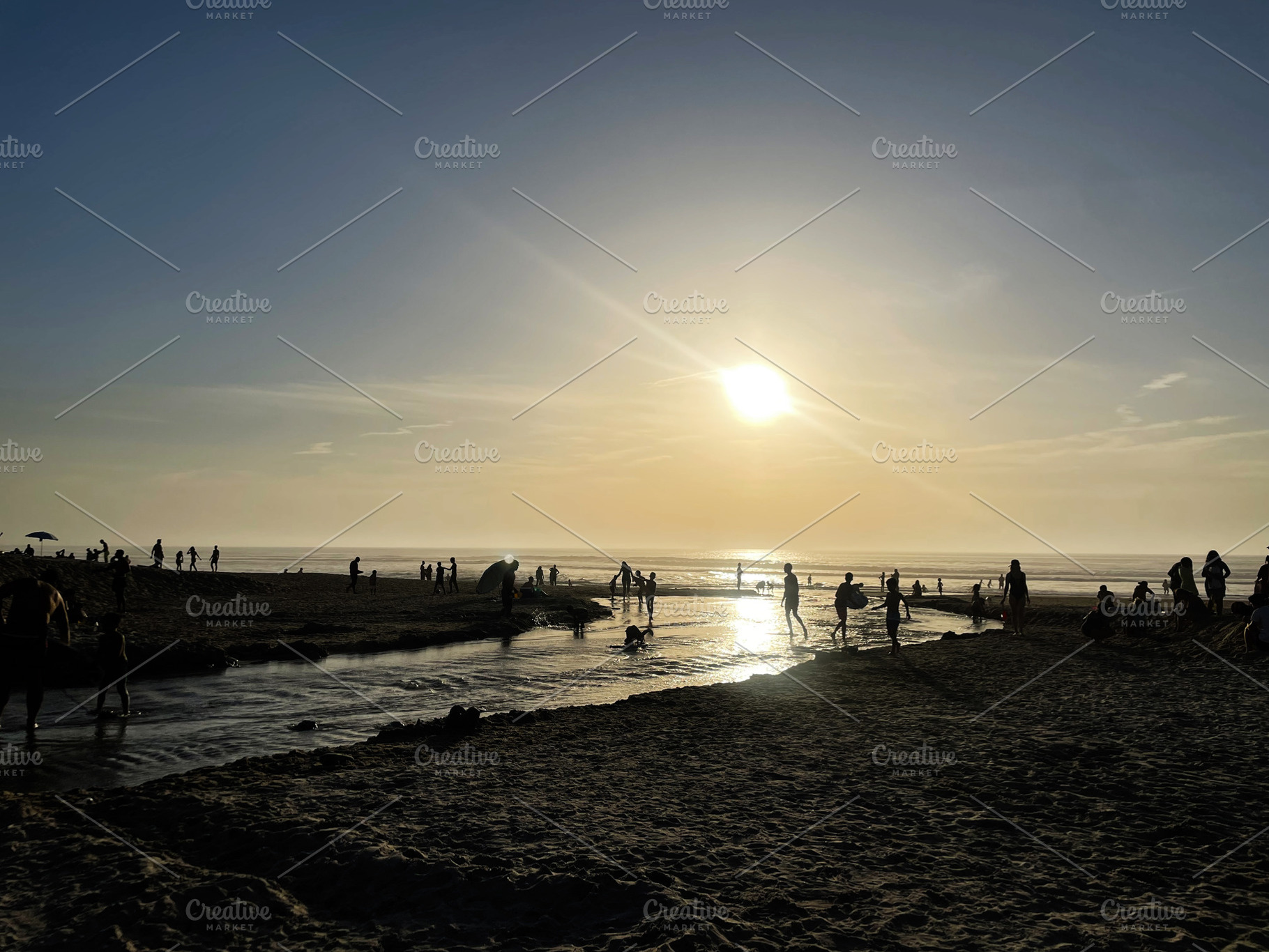 Silhouetted figures enjoying a tranquil sunset at the beach shoreline, a Photo by AS photostudio