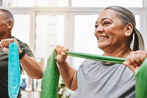Physiotherapy, stretching band and senior couple with teamwork for muscle wellness, rehabilitation and support together. Elderly black people or friends smile in physical therapy with strong progress, a Photo by Peopleimages.com