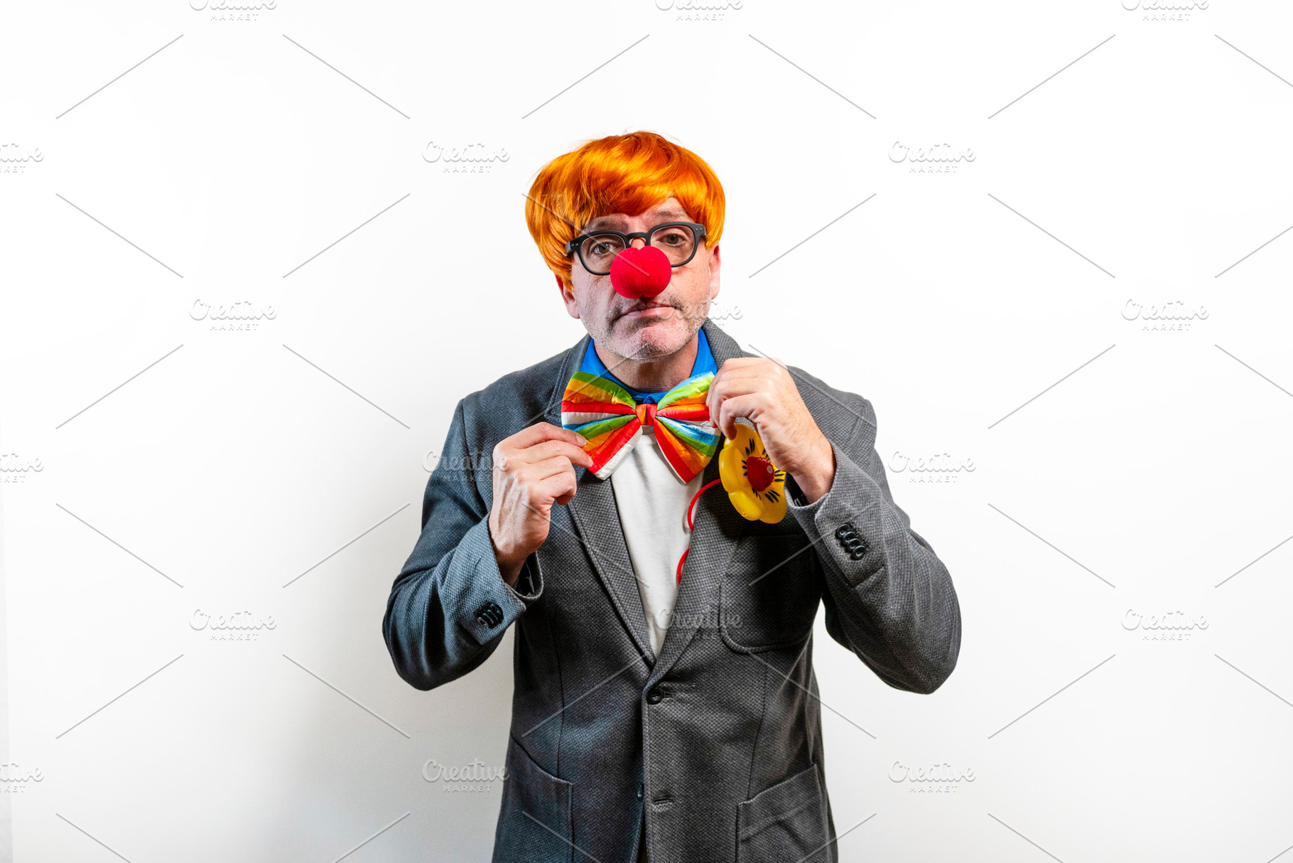Businessman wearing clown costume with red nose and rainbow bowtie, a Person Photo by karrastock