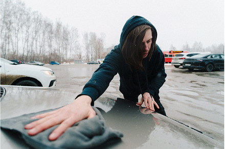 Person cleaning a car hood in a