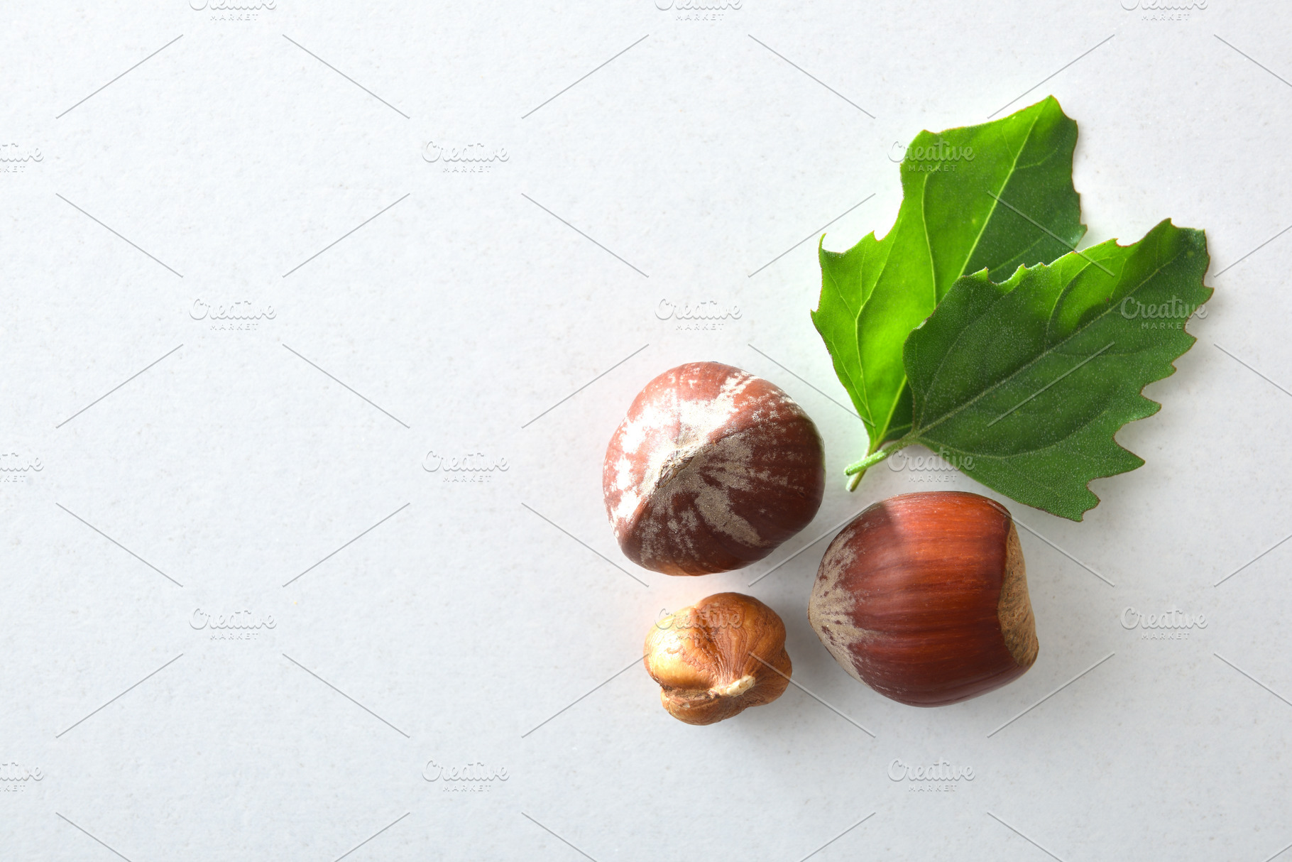 Three hazelnuts and two leaves isolated on white background, a Food & Drink Photo by Davizro's Market