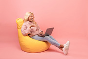 Happy woman relaxing in beanbag chair with laptop, female student using modern, a Photo by Prostock-Studio (Thumbnail 1 of 2)