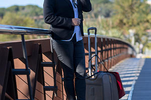 Businesswoman with suitcase walking on city bridge, a Photo by RF Images