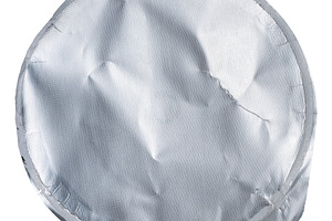 Close-up of a crumpled round foil yogurt lid on an isolated back, an Industrial Photo by ndanko