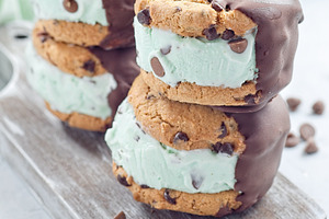 Mint chocolate chips ice cream and chocolate chips cookies sandwiches, on woode, a Food & Drink Photo by iuliia_n