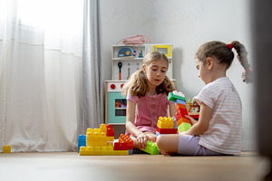 Two young girls playing with colorful building blocks on floor at home, a Person Photo by etorres69